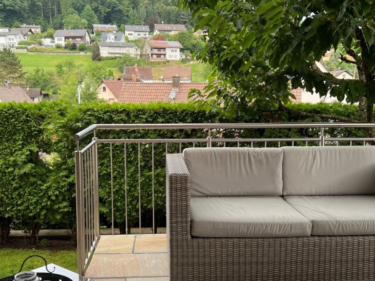 Schlafzimmer Gemütlicher Raum mit einem Sessel, einer Wand aus Glas und einem Bett im Hintergrund.