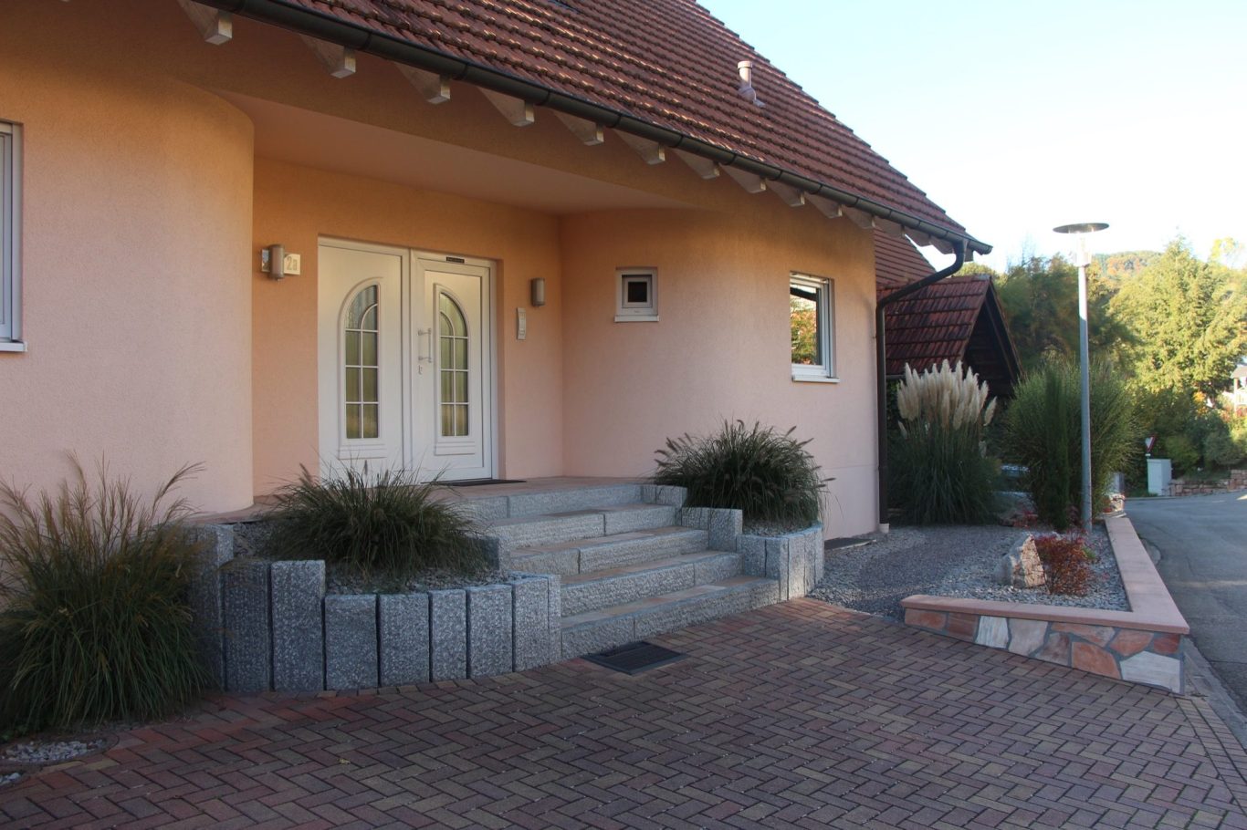 Haupteingang Eingang eines modernen Hauses mit einer Stufenanlage und üppiger Bepflanzung.